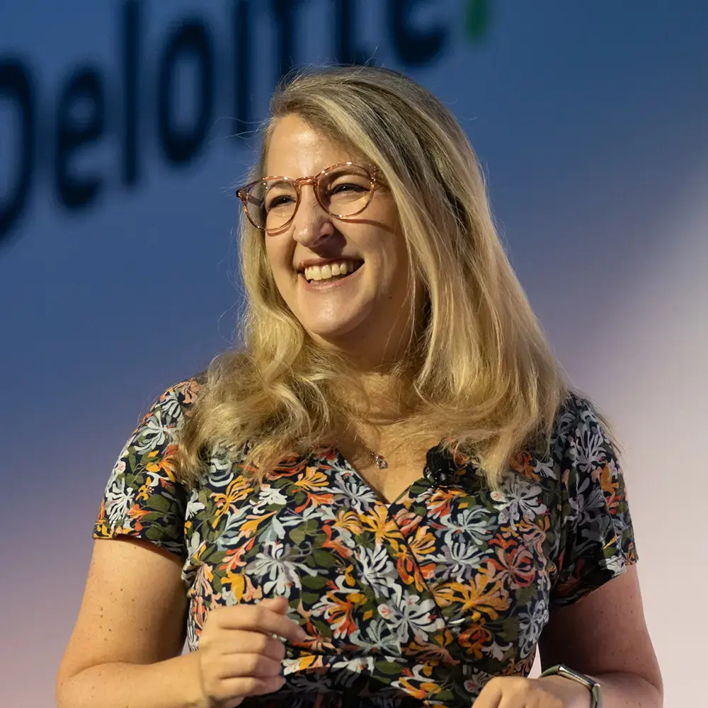 BecomingX COO Alexis Lambert on stage at an event for one of the 'big four'.