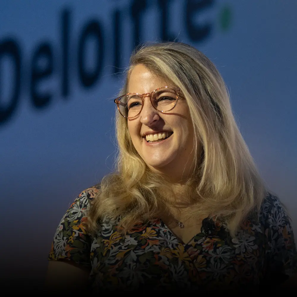 BecomingX COO Alexis Lambert on stage at an event for one of the 'big four'.